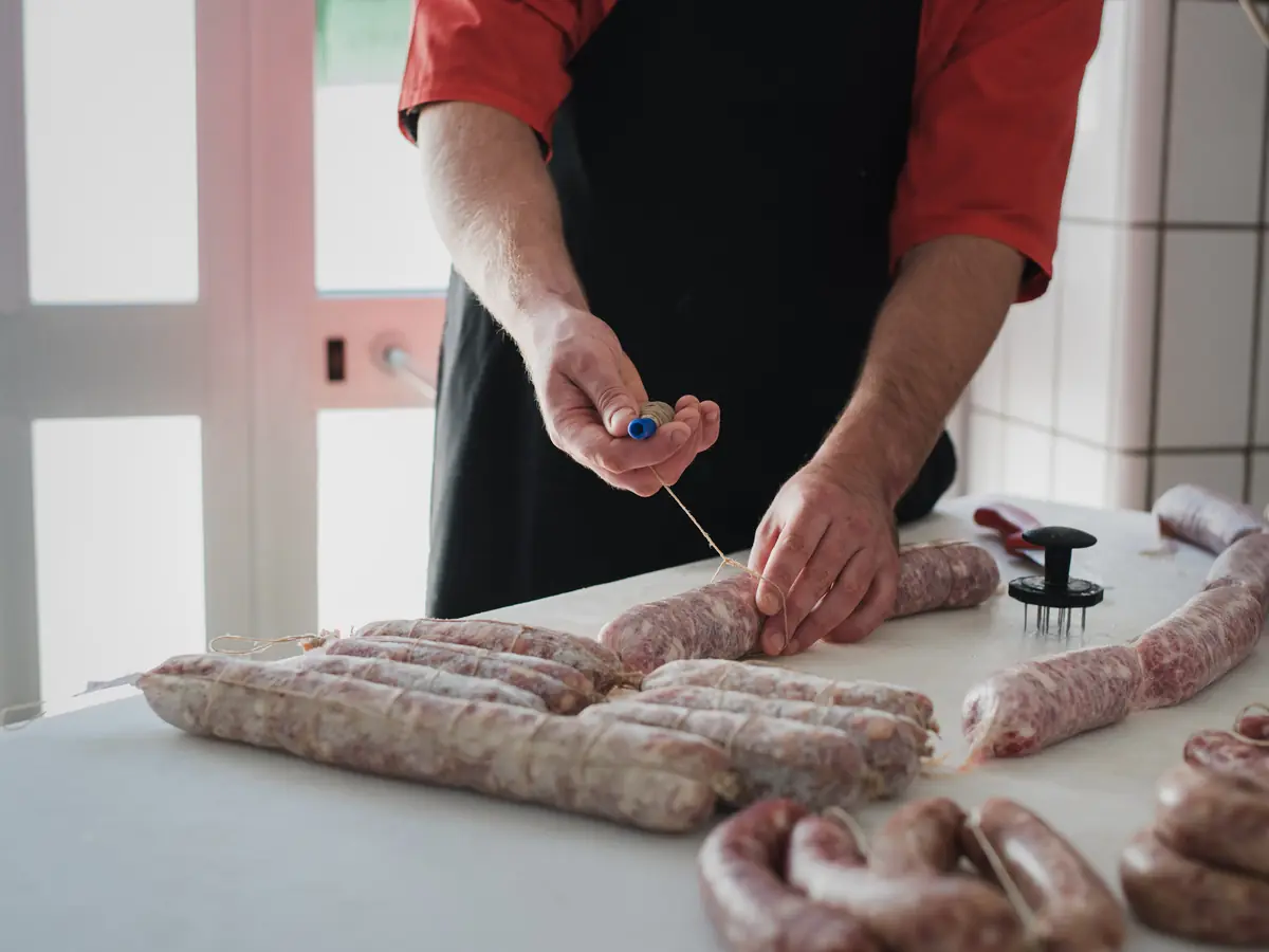Le mani che legano i salami con lo spago
